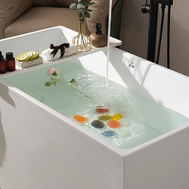 MonBlari white deep soaking bathtub filled with water, flower, and decorative stones