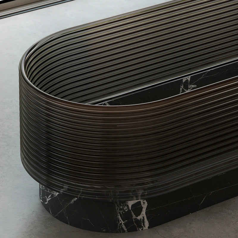 Sculptural veined marble bathtub with clear acrylic